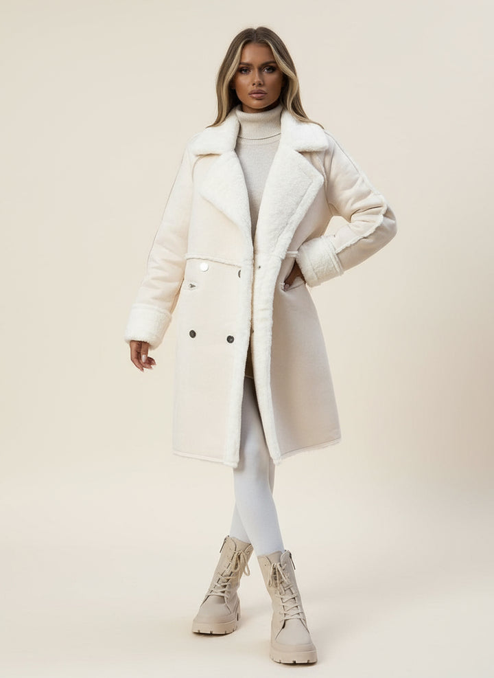 Person wearing a white coat and beige boots on a city street.