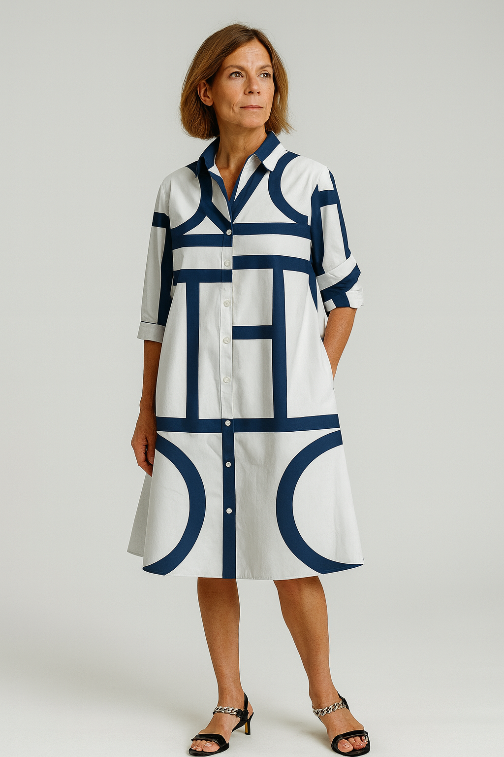Woman wearing a white dress with blue geometric patterns on a plain background