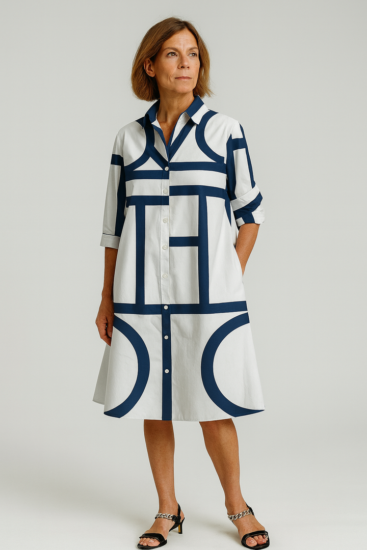 Woman wearing a white dress with blue geometric patterns on a plain background