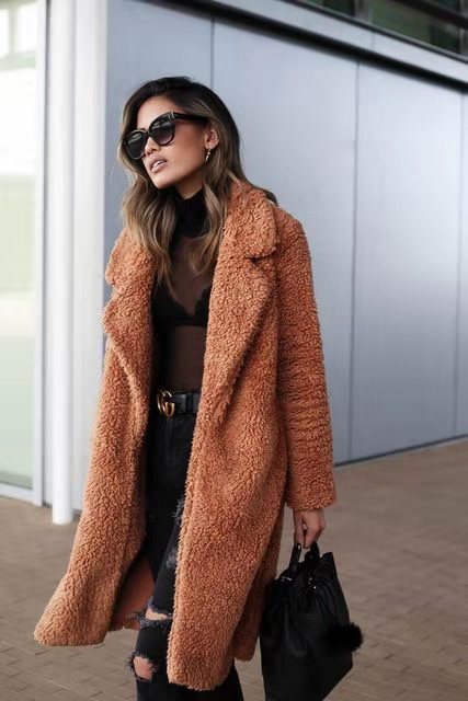 Woman wearing a brown teddy coat with sunglasses and a black handbag.